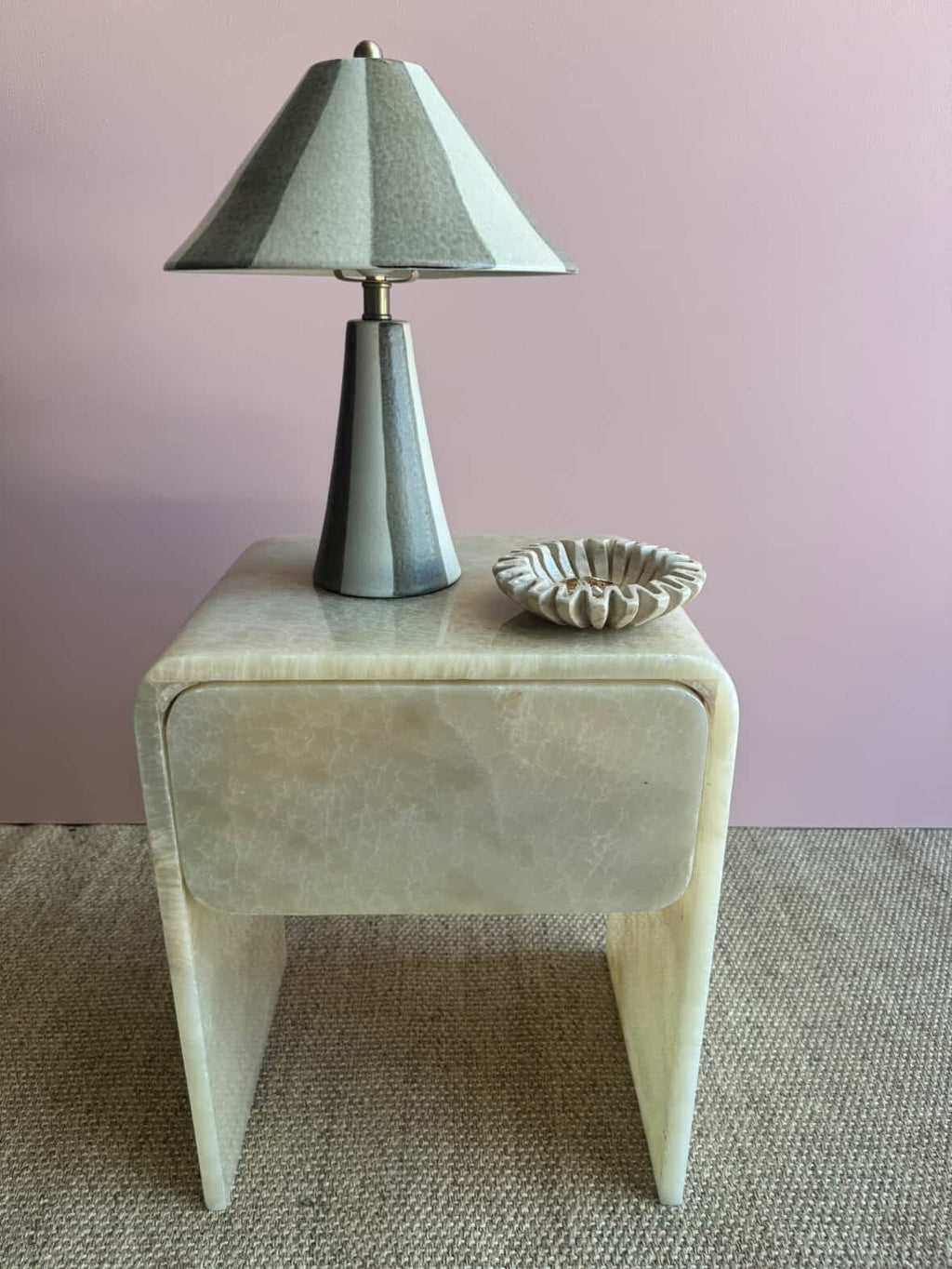 HC Homewares modern side table made of cream-colored stone with a single drawer and tapered legs.