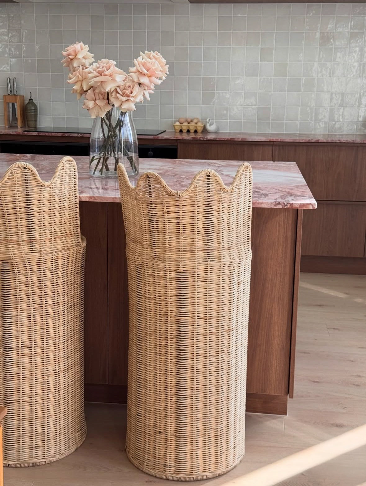 Two custom handcrafted natural rattan bar stools with a sculptural curved backrest, designed for luxury kitchen islands and contemporary interiors. Designed y HC Homewares.