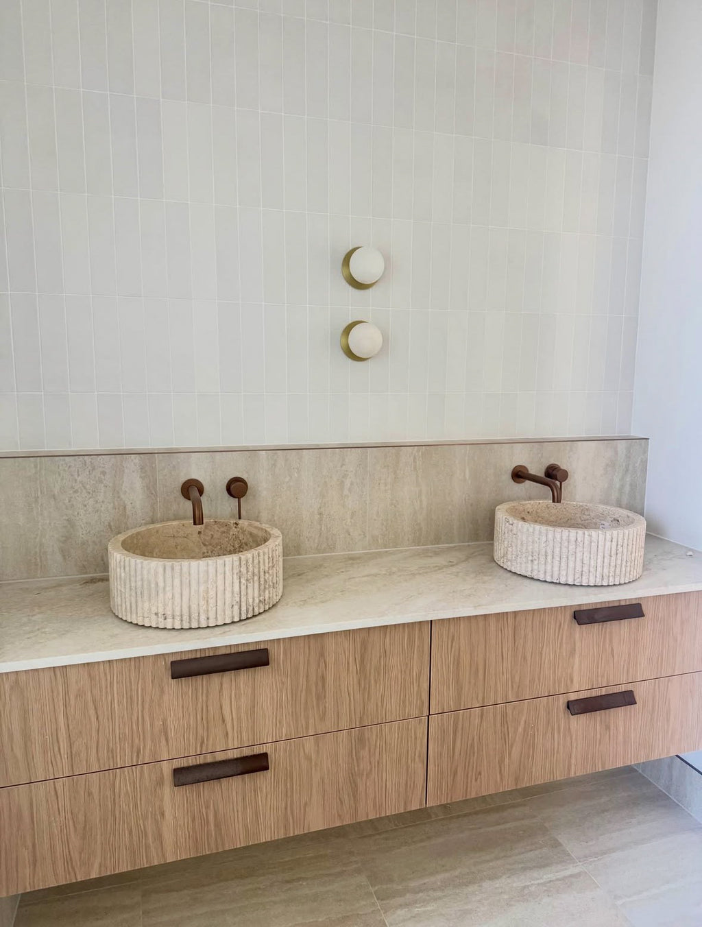 Fluted marble basins handcrafted from natural stone featuring a sculptural fluted exterior and round above-counter design in a luxury bathroom.