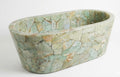 An oval, natural stone bath with a mosaic pattern of light green, beige, and gray polished fragments, designed by HC Homewares.