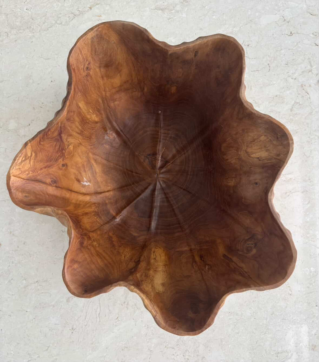 A rustic, handcrafted wooden bowl with a natural live edge and rich brown wood grain.