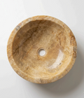 A round stone shallow bathroom basin with a beige and brown marbled texture, crafted from natural onyx stone.