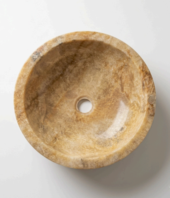 A round stone shallow bathroom basin with a beige and brown marbled texture, crafted from natural onyx stone.