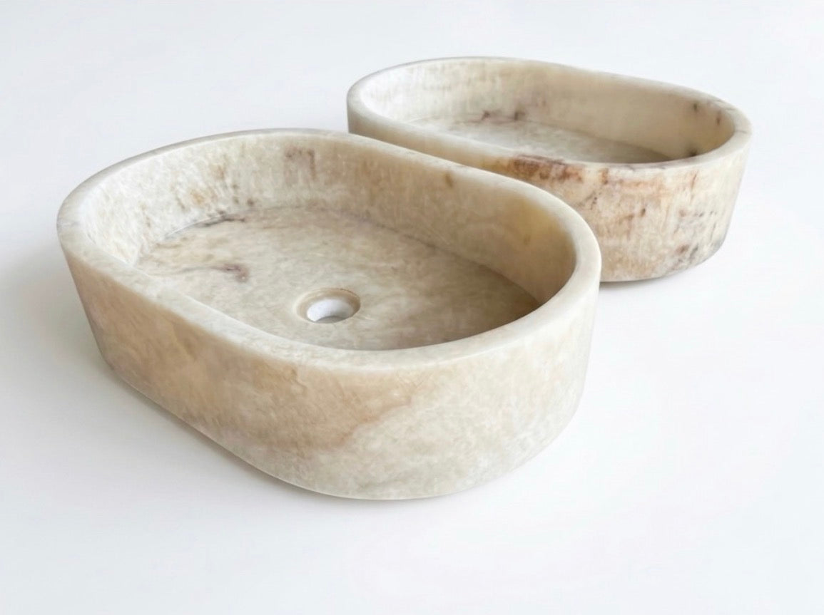 HC Homewares oval-shaped stone washbasins in a light beige marble-like finish.
