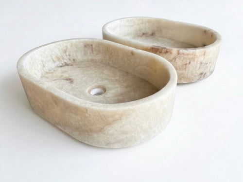 HC Homewares oval-shaped stone washbasins in a light beige marble-like finish.